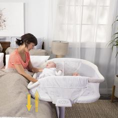 a woman holding a baby in a crib with an arrow pointing to the side