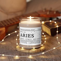 a lit candle sitting on top of a wooden table next to a string of lights