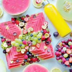 a table topped with watermelon, grapes and kiwis covered in fruit