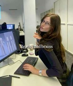 a woman sitting in front of a computer monitor with the words beauty and brains on it