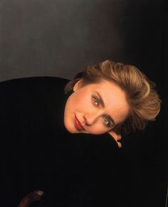 a woman with blonde hair and blue eyes posing for a photo in front of a black background