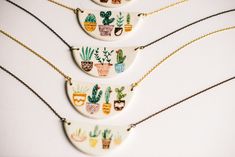 three necklaces with cactus designs on them are hanging from gold filled chains, along with black cords