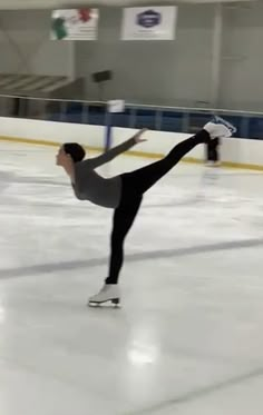 a man skating on an ice rink with one leg in the air and his arms out