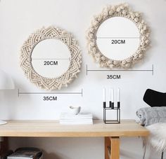 two circular mirrors hanging on the wall above a wooden table with white furnishing