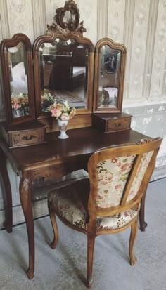 an antique desk with mirror, chair and vase