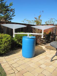 two large blue barrels sitting on top of a patio next to a table and chairs