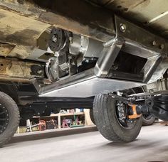 the rear end of a vehicle being worked on in a shop or repair area with tools underneath it