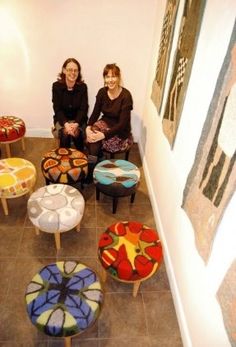 two women are sitting on stools in the middle of a room