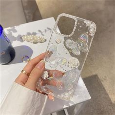 a person holding up a phone case that has butterflies on it and pearls around the edges