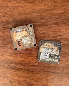 two small pieces of metal sitting on top of a wooden table next to each other