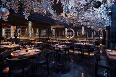 an empty restaurant with tables and chairs covered in blue flowers hanging from the ceiling above