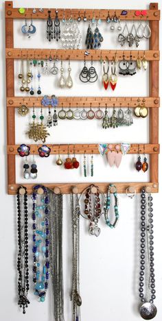 a wall mounted jewelry organizer with wooden pegs