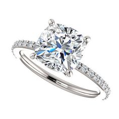 a cushion cut diamond engagement ring with pave set diamonds on the shoulders and sides