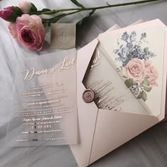 wedding stationery with roses and wax stamp on it next to a bouquet of flowers