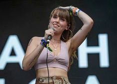 a woman holding a microphone up to her head while standing in front of a stage