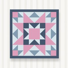 a pink, blue and grey quilt hanging on a wall next to a striped wall