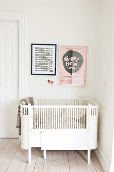 a baby's room with white walls and wooden floors, including a crib