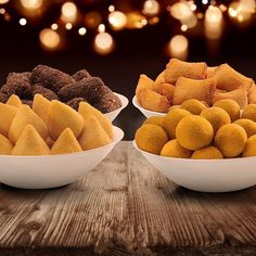 three bowls filled with different types of desserts on top of a wooden table in front of lights