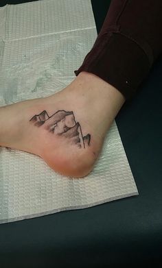 a person with a mountain tattoo on their foot