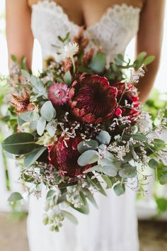 a bride holding a bouquet of flowers and greenery