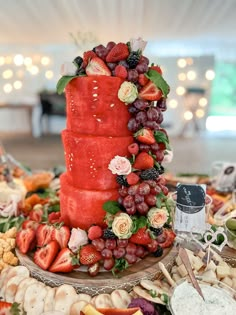 there is a red cake with fruit on the top and flowers on the bottom, surrounded by other food items