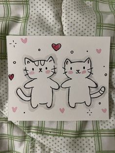 two cats are standing next to each other on a sheet of paper with hearts in the background