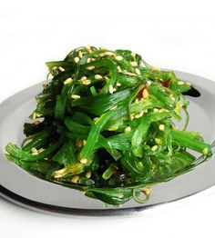 a white plate topped with green vegetables covered in seasoning and sprinkles