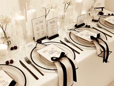 the table is set with black and white place cards, silverware, and candles