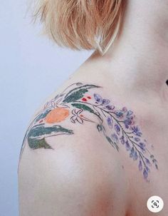 the back of a woman's shoulder with flowers and leaves tattooed on her arm