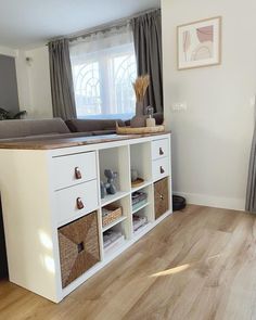 a living room filled with furniture and lots of storage under a window next to a wooden floor