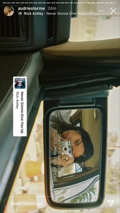 a woman taking a selfie in the side view mirror of a car with her cell phone