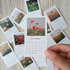 a person holding up a calendar with pictures of flowers on it in front of them