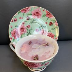 a tea cup filled with liquid and pink flowers