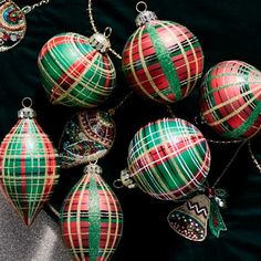 christmas ornaments are arranged on a black background with green and red plaid ribbon around them