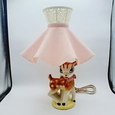 a lamp that is on top of a table with a deer figurine underneath it