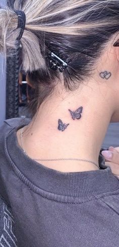 a woman's neck tattoo with two butterflies on the back of her left shoulder