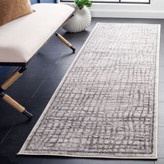 a large rug in a living room next to a couch and chair with a plant on it