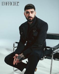 a man sitting in a chair with tattoos on his arm