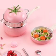 a pink pot and pan filled with food next to utensils on a pink surface