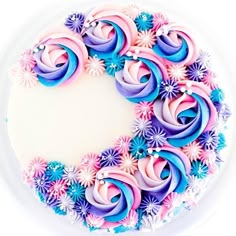 a cake decorated with pink, purple and blue icing on a white platter