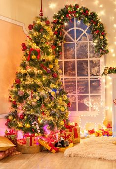 a decorated christmas tree in front of a window with lights and presents under the tree