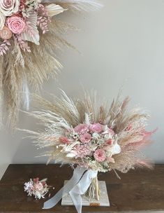 two bouquets of flowers are sitting on a table next to some dried grass and pink carnations