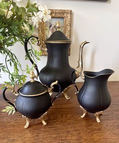 three black vases sitting on top of a wooden table