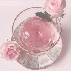 two pink roses sit in a glass bowl