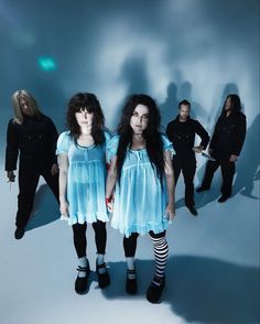 three women in blue dresses standing next to each other with their shadows on the wall behind them