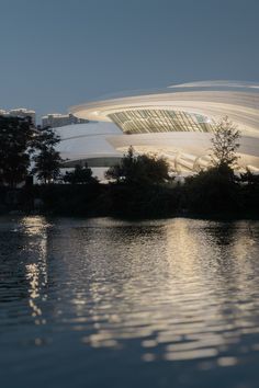 a large building sitting on top of a lake next to a tall white structure in the distance