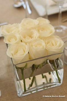 white roses in a clear vase on a table