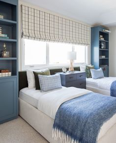 two beds in a room with blue walls and white carpeted flooring, along with built - in bookshelves