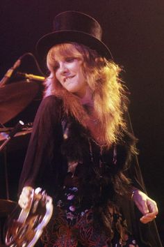 a woman in a black hat and dress on stage