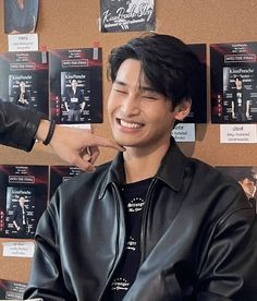 a young man is smiling while getting his hair brushed by another person's hand